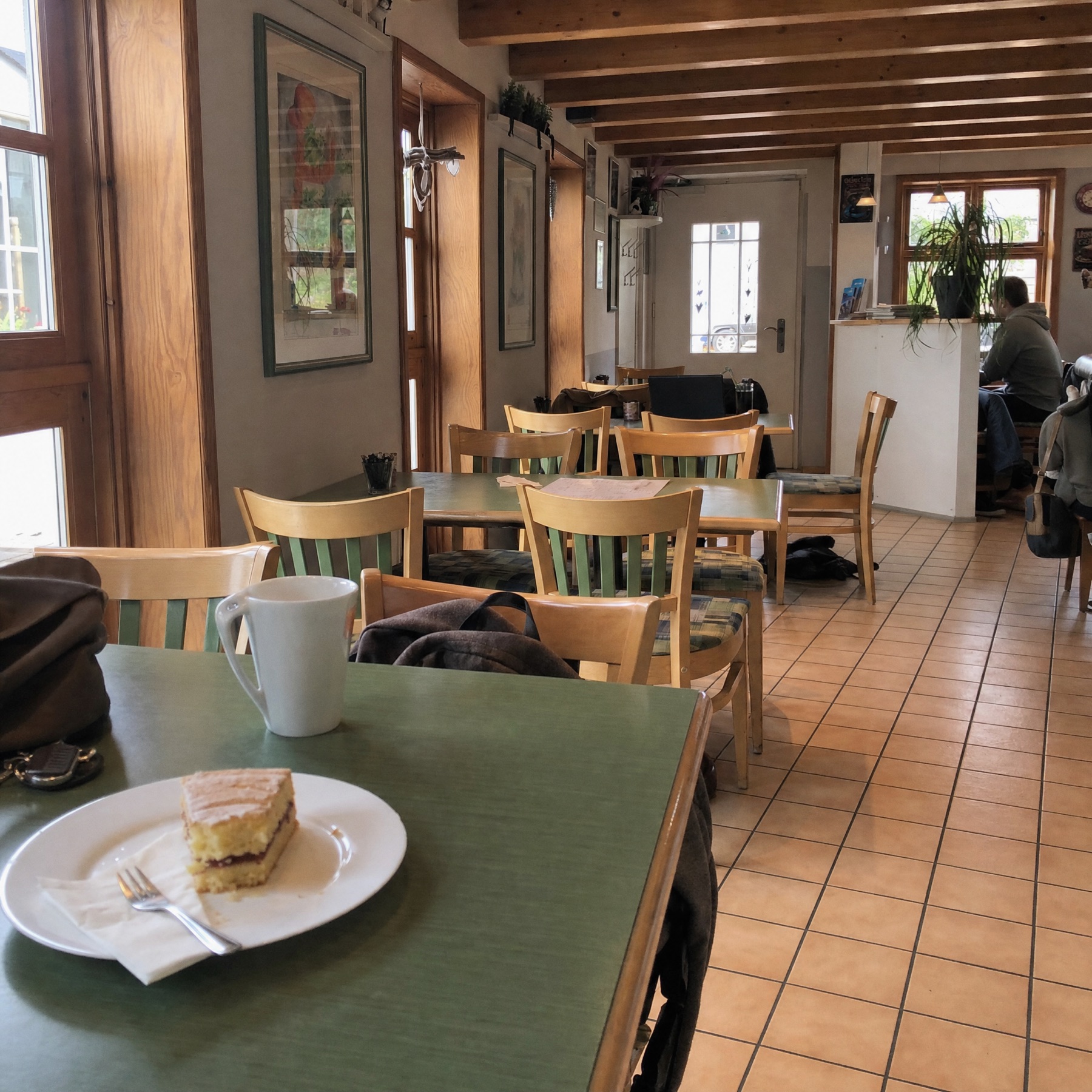 Gemütlicher Innenraum des Cafés mit Holzbalken, Pflanzen und gedecktem Tisch